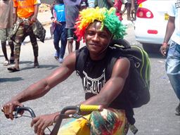 young man on bike with Ghana wig